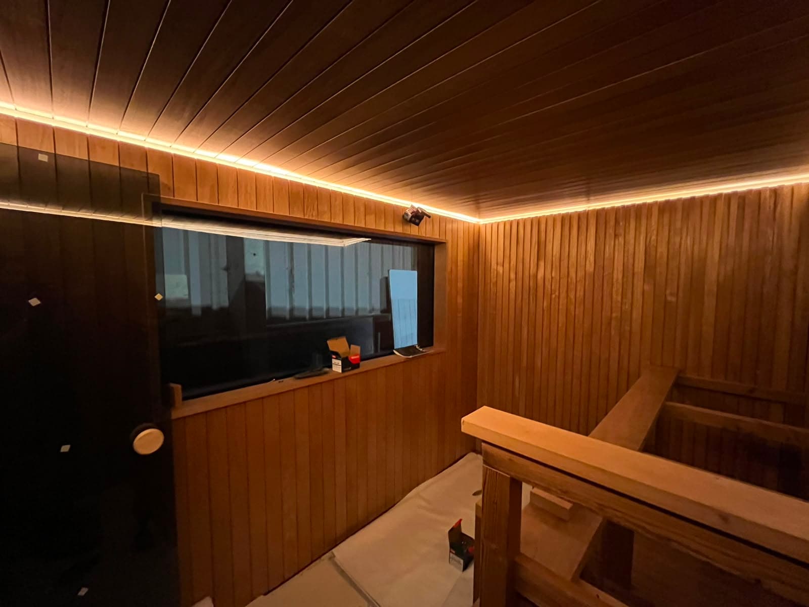 Inside the Bosham Sauna build: timber-lined walls and ceiling, a long window and the bench frame going in.